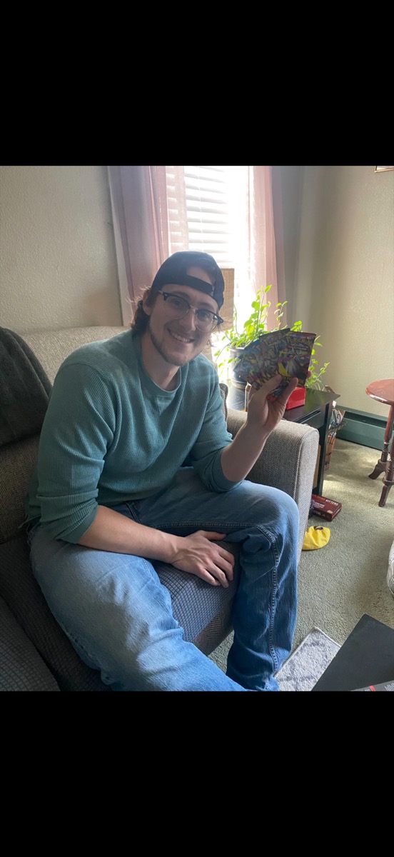 Eli Larkin smiling and holding up Pokemon card packs