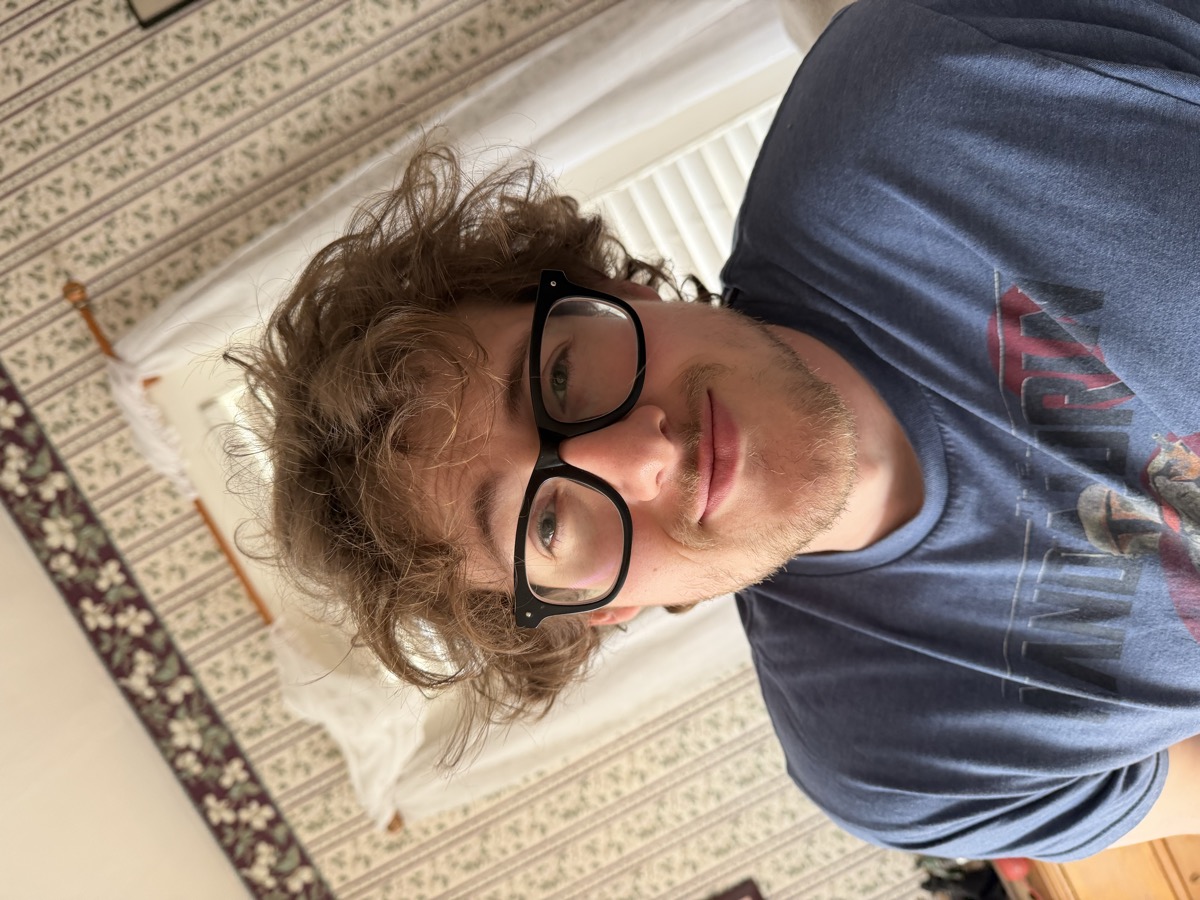 Eli Larkin with big morning curls in a Mandalorian shirt