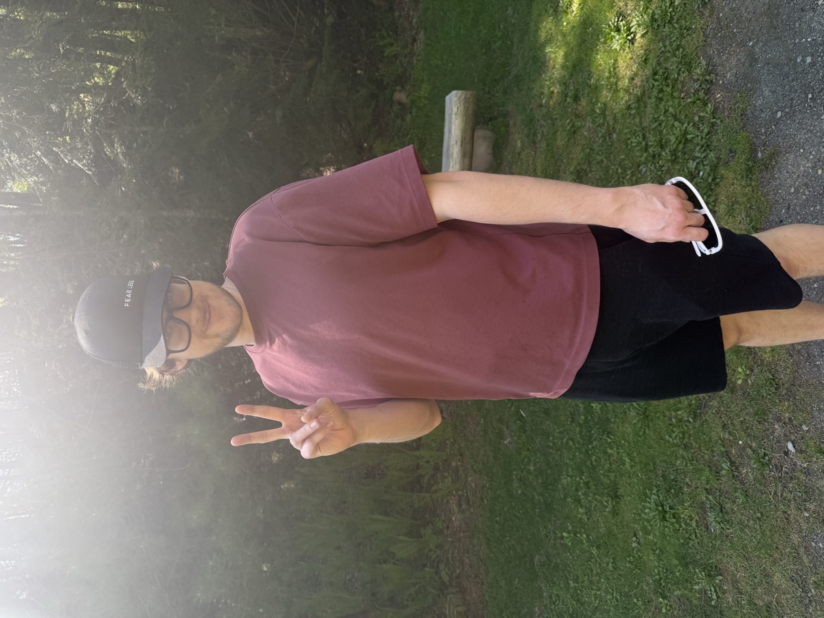 Eli Larkin flashing a peace sign on a sunlit trail