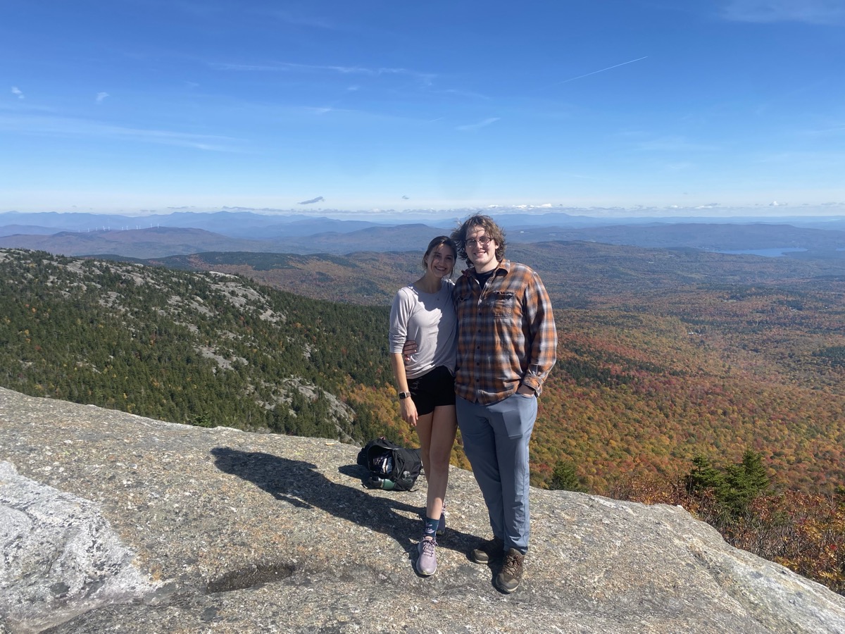 Eli Larkin and Camille on a mountain summit above fall foliage