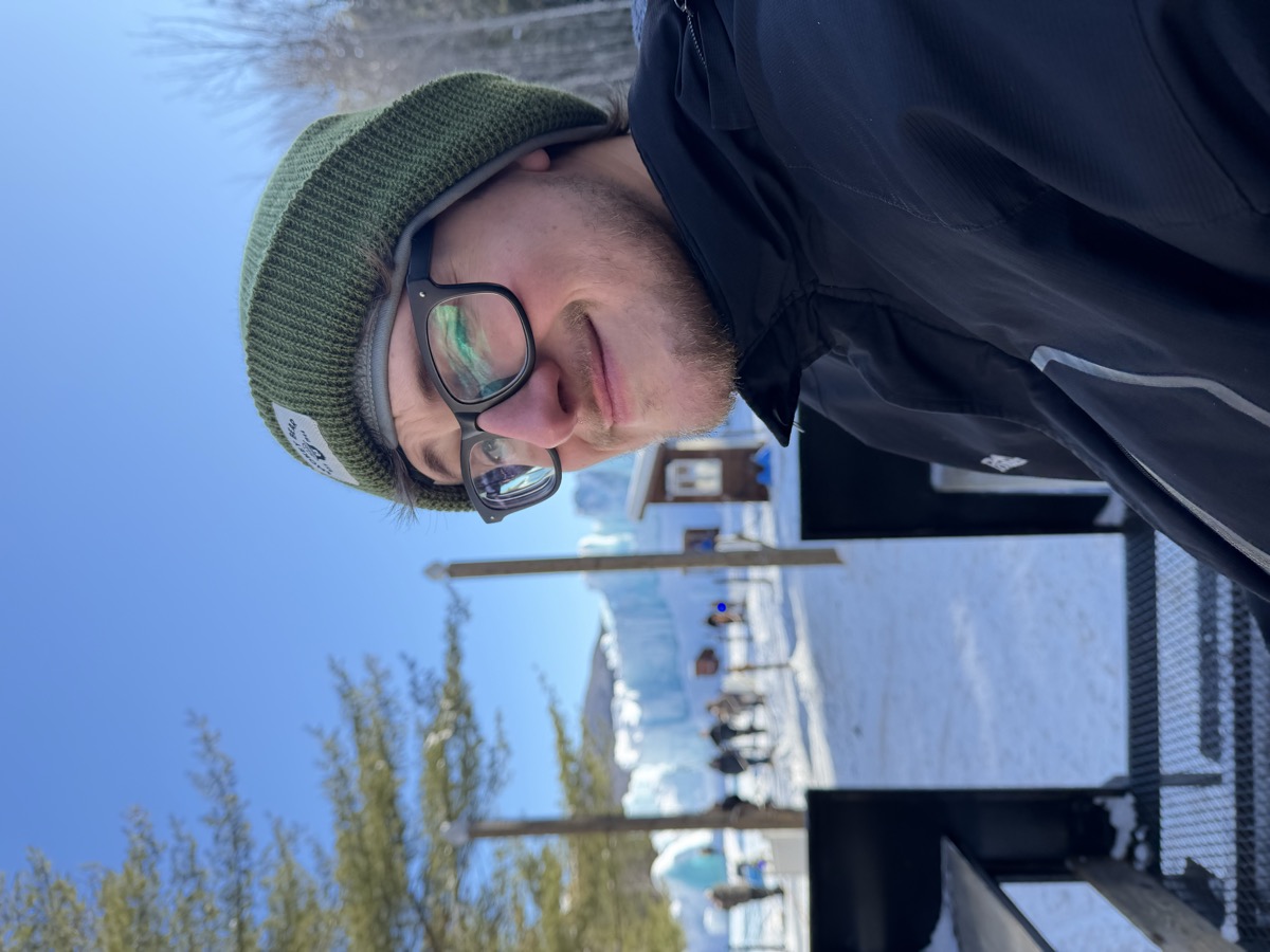 Eli Larkin in a green beanie in front of ice castles