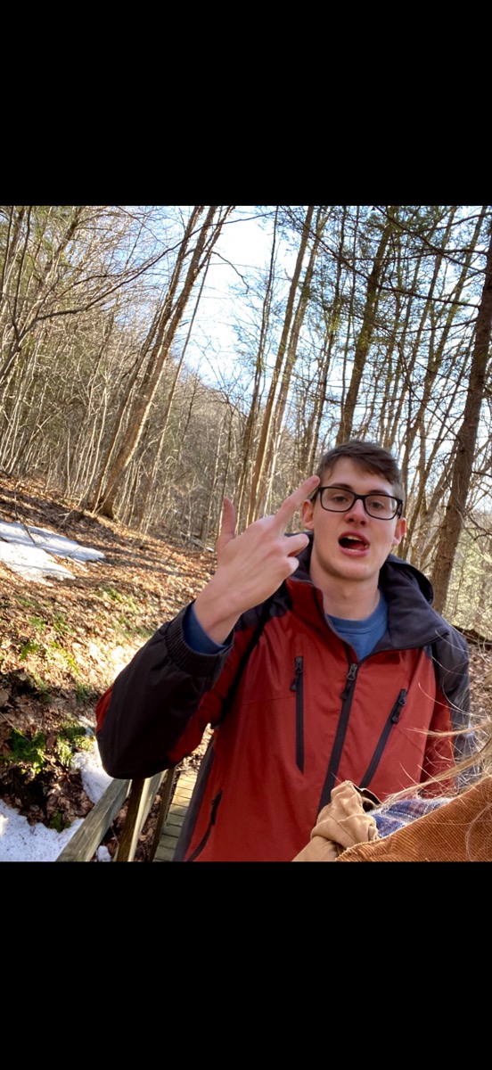 Eli Larkin in the woods mid-sentence with a hand gesture